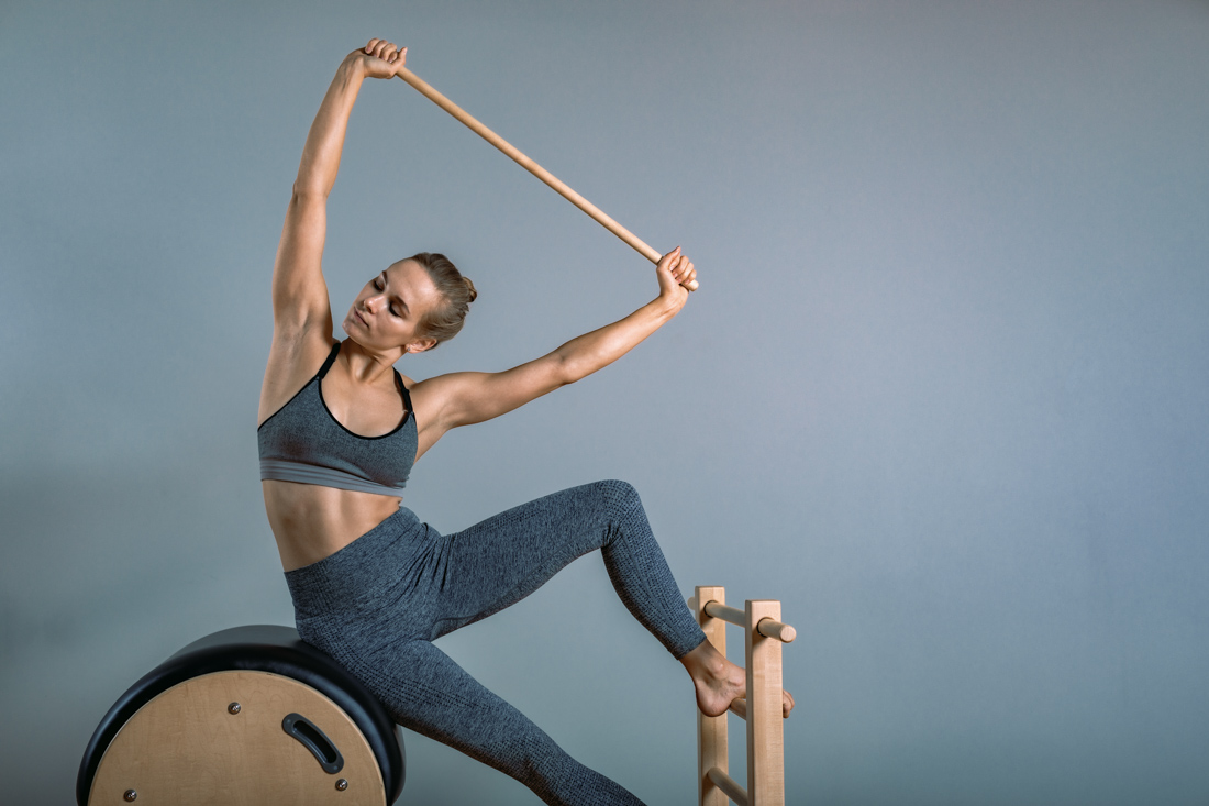 Woman stretching forward on Pilates reformer machine