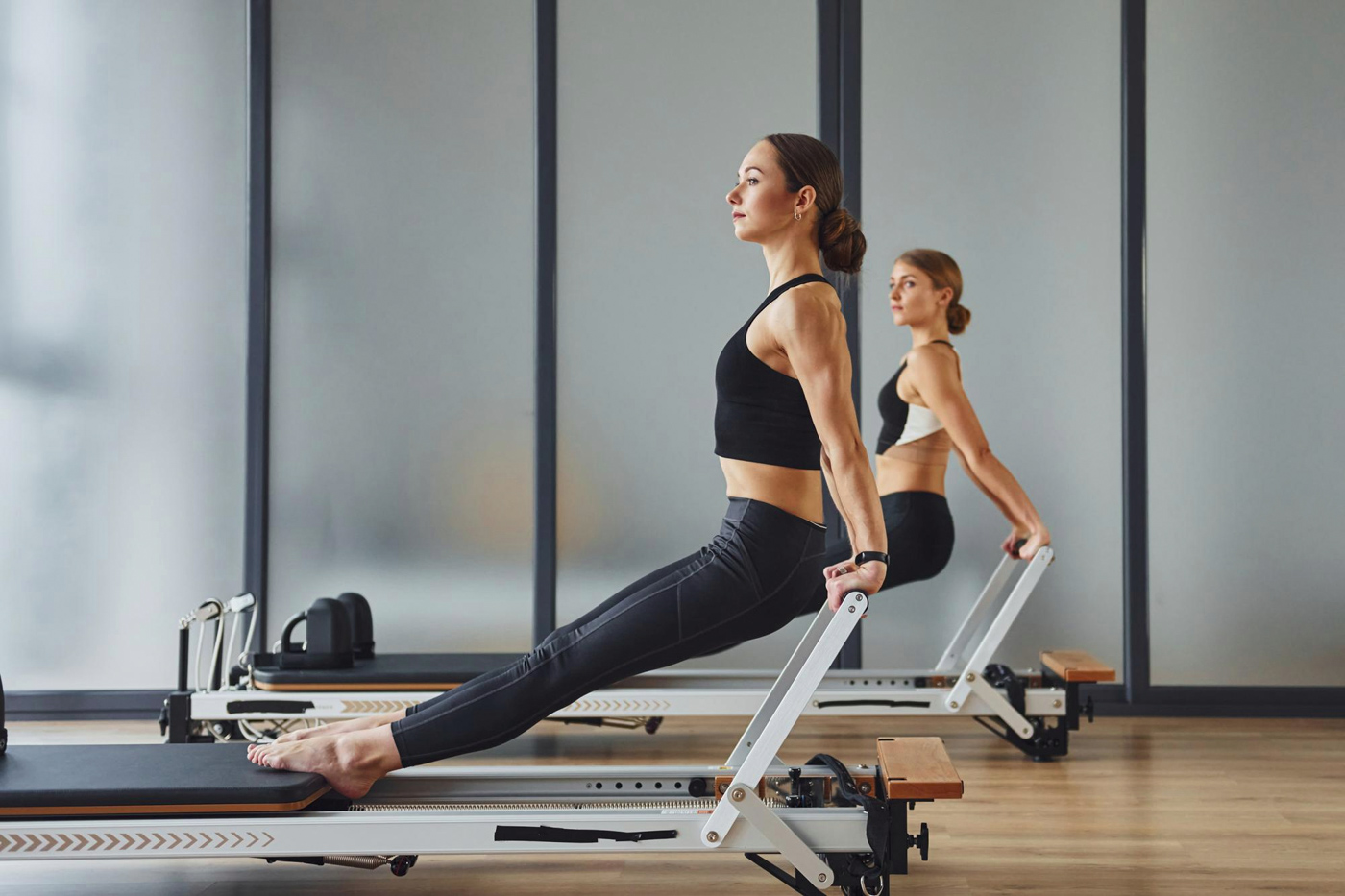 Two women doing a Pilates reformer workout
