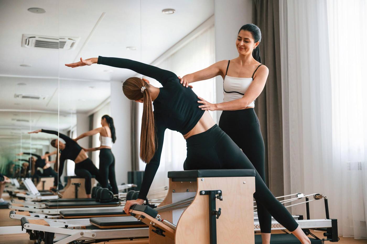Instructor guiding Pilates stretch on reformer